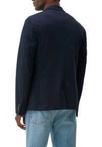 Marineblaues Blazer aus leichtem Stoff, mit modernem Schnitt, Reverskragen und geknöpften Ärmeln, kombiniert mit hellblauen Jeans.