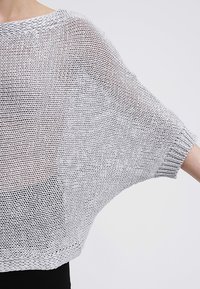 Hellgrauer, locker sitzender Strickpullover mit Fledermausärmeln und gerippten Bündchen, der ein strukturiertes, offenes Webdesign aufweist.
