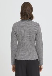 Blazer aderente a righe grigie e nere con maniche lunghe, tessuto liscio e taglio sartoriale. La parte posteriore presenta una cucitura verticale.