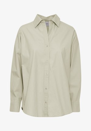 Svetlozeleni srajčni zgornji del, izdelan iz mehkega in gladkega materiala. Ima klasičen ovratnik, dolge rokave in rahlo ukrivljen rob.