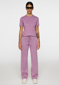 Lavender t-shirt met ronde hals en bijpassende sweatpants met trekkoord, met een losse pasvorm. Grijze sneakers met een gestructureerde zool.