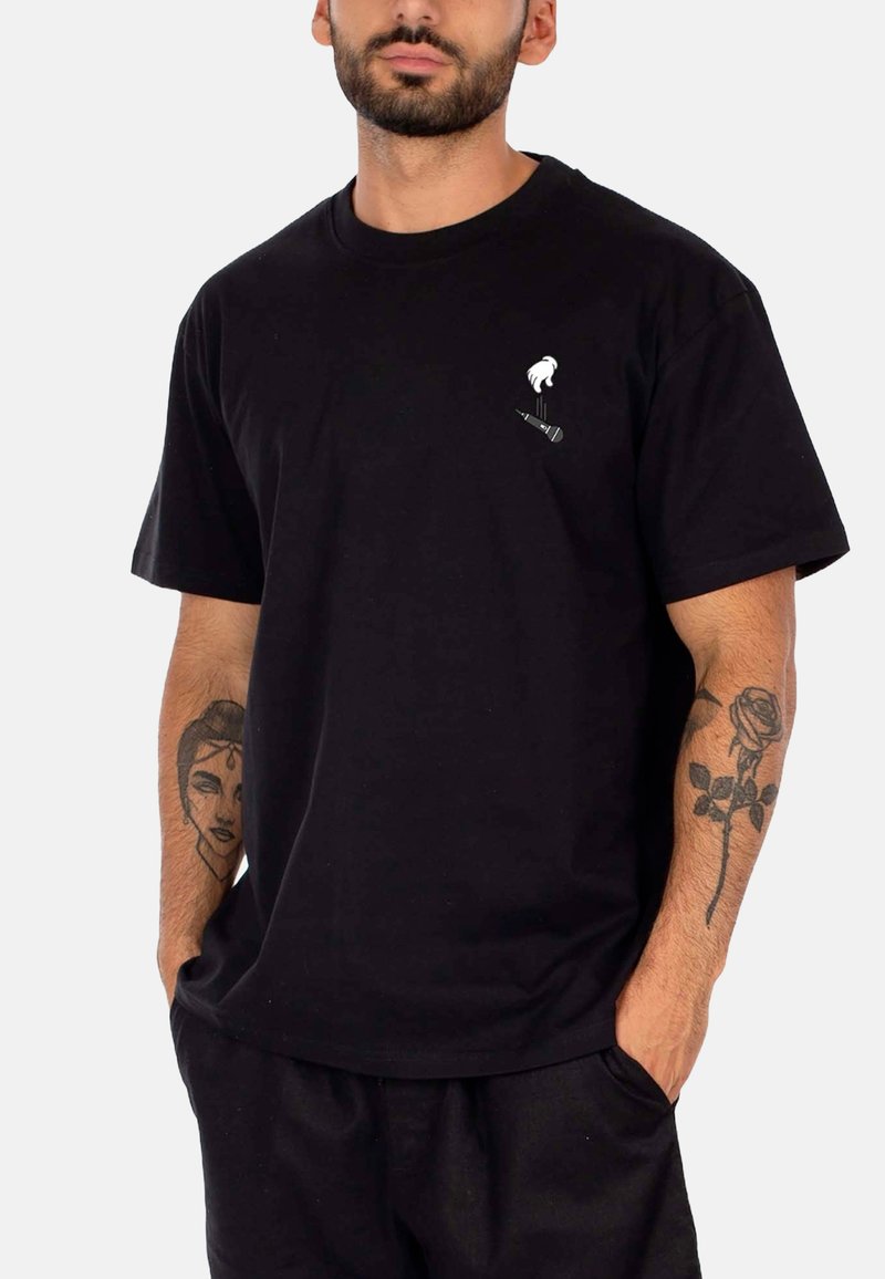 Zwarte katoenen t-shirt met een kleine witte afbeelding van een hand en een microfoon op de linkerkant van de borst. Korte mouwen, relaxed fit.