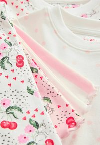 Mehrfarbige Baumwolloberteile mit floralen, Kirsch- und Herzmustern sowie Texturen wie gepunktet und in einfarbigen Designs, variierenden Ausschnitten.