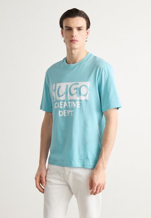 Turquoise cotton t-shirt featuring a white graphic print with the text "HUGO CREATIVE DEPT." Short sleeves, crew neck, relaxed fit.