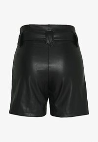 Mustat tekonahkaiset korkeavyötäröiset shortsit, joissa on leveä vyö ja keskimmäinen sauma takana, esitellään takapainotteisesti valkoista taustaa vasten.