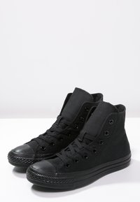 Sneakers alte nere in tela, con punta rotonda, suola in gomma e occhielli metallici con lacci piatti. Superficie superiore testurizzata.
