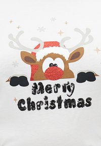 Tricou alb cu un cap de ren cu nas roșu, antlers gri și albi, mănuși negre și text "Crăciun fericit" din paiete.
