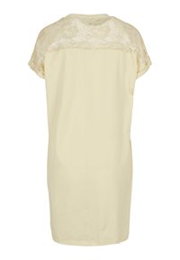 Robe à manches courtes de couleur crème avec un panneau arrière en dentelle. Tissu lisse avec une coupe décontractée et une silhouette droite. Aucune fermeture visible.