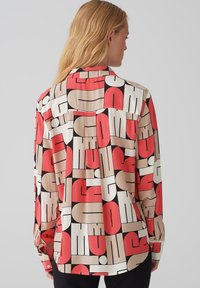 Langarmshirt met een geometrische print in rood, beige en zwart. Glad materiaal, knoopmanchetten en een gespleten schouderpas.