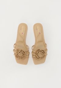 Brown slide sandals with a square toe, featuring three straps and a woven flower accent on the top. Sole has a smooth finish.