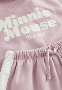 Lyserød sweatshirt med fed hvid tekst "Minnie Mouse" og "Siden 1928." Inkluderer en snor i taljen og en blød tekstur.