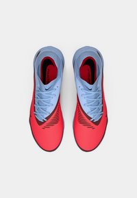 Rote und blaue Sportschuhe mit strukturierten Oberflächen, runder Zehenpartie und auffälligen, gemusterten Akzenten. Verfügt über hellblaue Schnürsenkel und ein Logo.