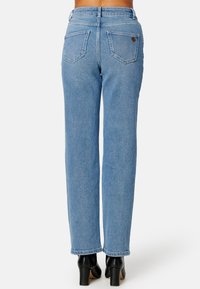 Jasnoniebieskie dżinsy z prostą nogawką, z dwoma tylnymi kieszeniami i małą skórzaną metką z logo blisko pasa.