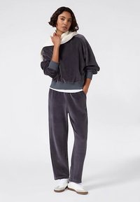 Velvet two-piece lounge set in dark gray, featuring a loose-fitting sweatshirt with a wide collar and matching trousers with an elastic waistband.