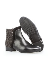 Bottes noires en cuir au niveau de la cheville avec un panneau en daim imprimé léopard, des accents de clous en argent et une semelle en caoutchouc texturée. Conception à bout carré.