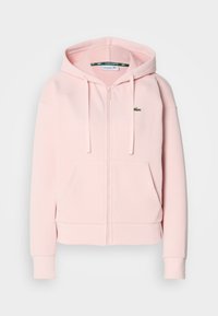 Haut de sweat à capuche rose à zip, fabriqué en tissu doux, avec une poche kangourou, des poignets côtelés et un petit logo crocodile brodé sur la poitrine gauche.