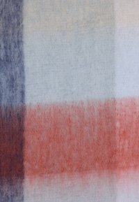 Geruit stof in zachte wol, met tinten lichtblauw, donkerblauw en roestbruin, met een fuzzy textuur en subtiele verloop.