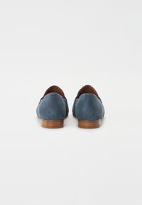 Kék velúr loaferek sima textúrával, alacsony fából készült sarokkal és varrott díszítéssel. Lekerekített hát és slip-on kialakítás.