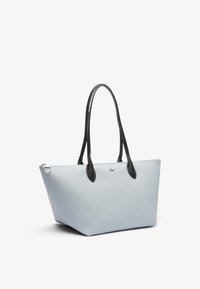 Borsa tote azzurro chiaro con manici in pelle nera, forma rettangolare, accessori in argento e superficie testurizzata.