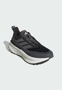 Chaussure de sport noire avec tige en maille, logo distinct à trois bandes, semelle intermédiaire blanche épaisse et semelle extérieure en caoutchouc noir texturé pour une traction optimale.
