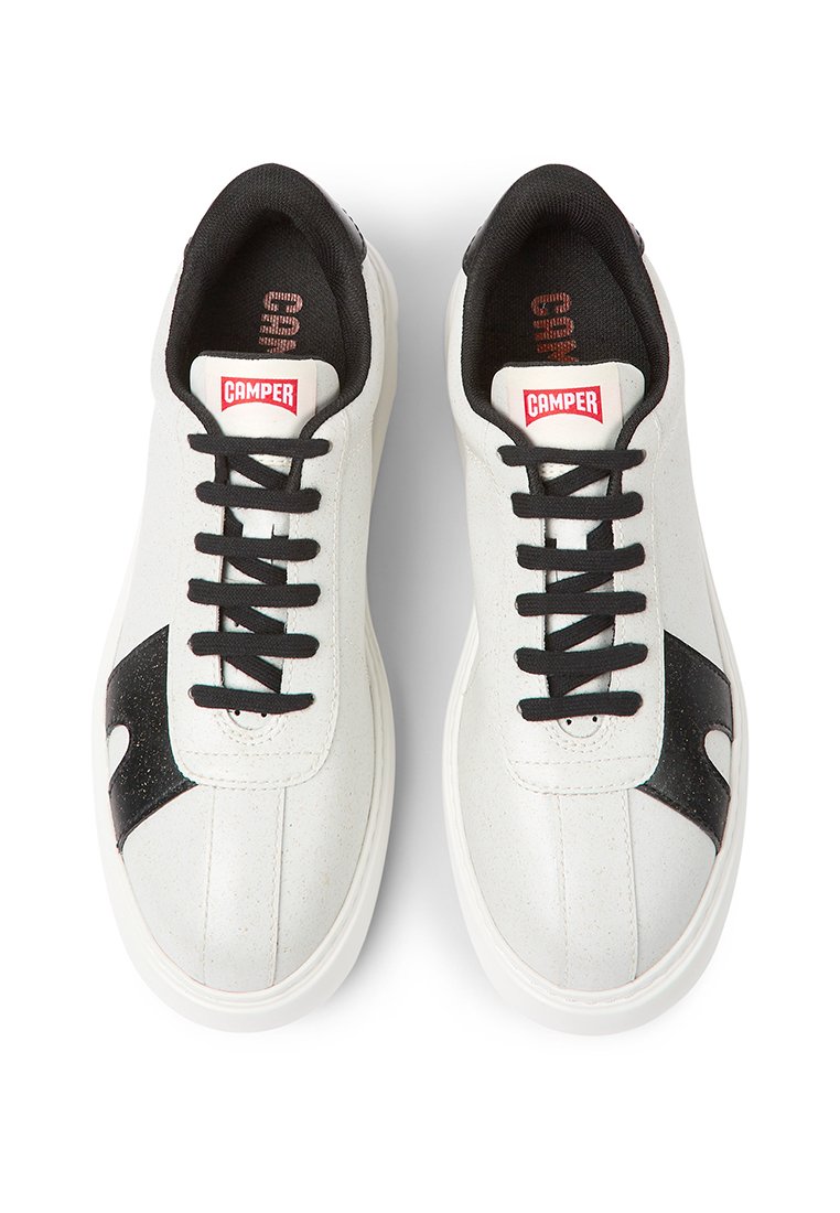 Zapatillas blancas con cordones negros y acentos laterales, logo rojo de Camper en la lengüeta y cuello acolchado negro, vistas desde arriba.