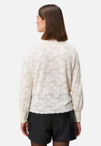 Spitzenpullover in Off-White mit floralem Muster, langen Ärmeln, gerippten Bündchen und lässiger Passform. Weiche Textur mit leichtem Finish.