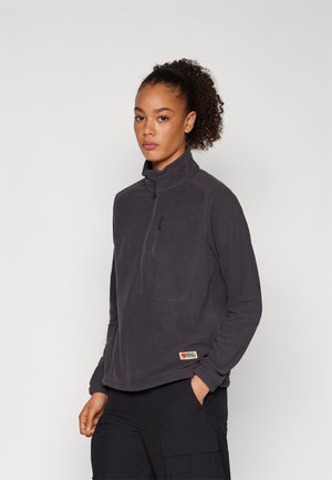 Dark gray fleece pullover with a high collar, featuring a zippered chest pocket and a tag on the left hem. Soft texture, relaxed fit.