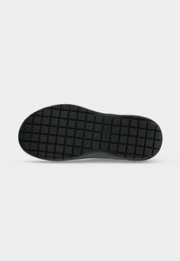 Semelle de chaussure avec motif quadrillé en caoutchouc noir, affichant le nom de la marque "BIRKENSTOCK" au centre de la semelle.