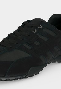Baskets décontractées noires avec semelle texturée, devant à lacets, panneaux supérieurs en daim et mesh.