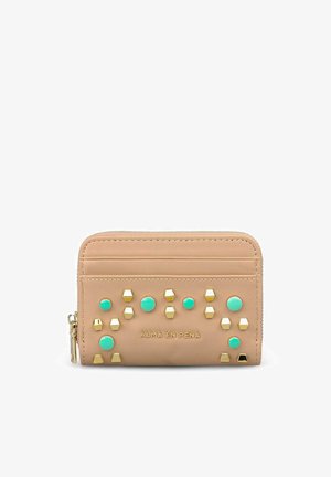 Cartera beige de cuero con cremallera, tachuelas doradas y turquesas y logo de Alma en Pena en el frente, con ranuras para tarjetas en el borde superior.