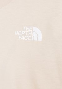 T-shirt in cotone beige con logo stampato bianco "THE NORTH FACE" e design a mezzaluna, realizzato in tessuto liscio e strutturato.