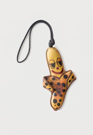 Portachiavi in pelle a forma di banana sbucciata con macchie nere e un volto sorridente disegnato, attaccato a un laccio nero a forma di anello.