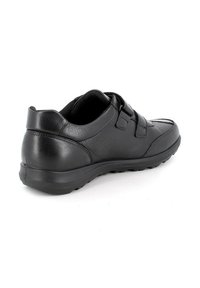 Scarpa in pelle nera con due cinturini in Velcro, punta arrotondata, superficie testurizzata e suola in gomma robusta. Presenta dettagli di cucitura minimi.