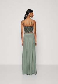 Top curto floral com alças finas emparelhado com uma saia maxi verde, fluida, com faixa elástica na cintura. Textura suave e corte descontraído.
