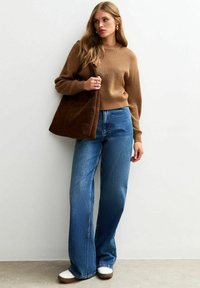 Brun ribbad stickad tröja, blå högmidjade vida jeans, brun mockaväska och vita sneakers med bruna accenter.