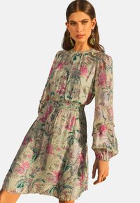 Rochie cu imprimeu floral dintr-un material ușor, ce dispune de o talie elastică, mâneci lungi tip puff și o margine volanată, cu accente verzi, roz și metalice.