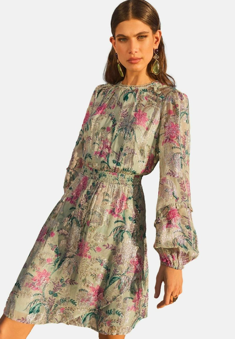 Rochie cu imprimeu floral dintr-un material ușor, ce dispune de o talie elastică, mâneci lungi tip puff și o margine volanată, cu accente verzi, roz și metalice.