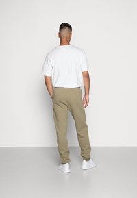Vit kortärmad T-shirt, beige sweatpants och vita sneakers. Outfiten har en avslappnad passform och ett enkelt mönster.