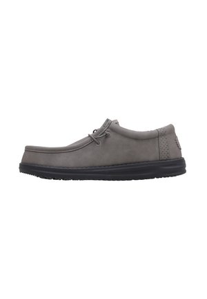 Zapatos de cuero gris con un diseño de perfil bajo, detalle de cordones y suela de goma negra. Presentan una textura suave y un minimalismo en las costuras.