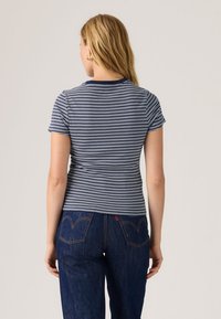T-shirt met marineblauwe en witte strepen, korte mouwen, slim fit, ronde hals, zachte stof, weergegeven van achteren, gecombineerd met donker denim jeans.