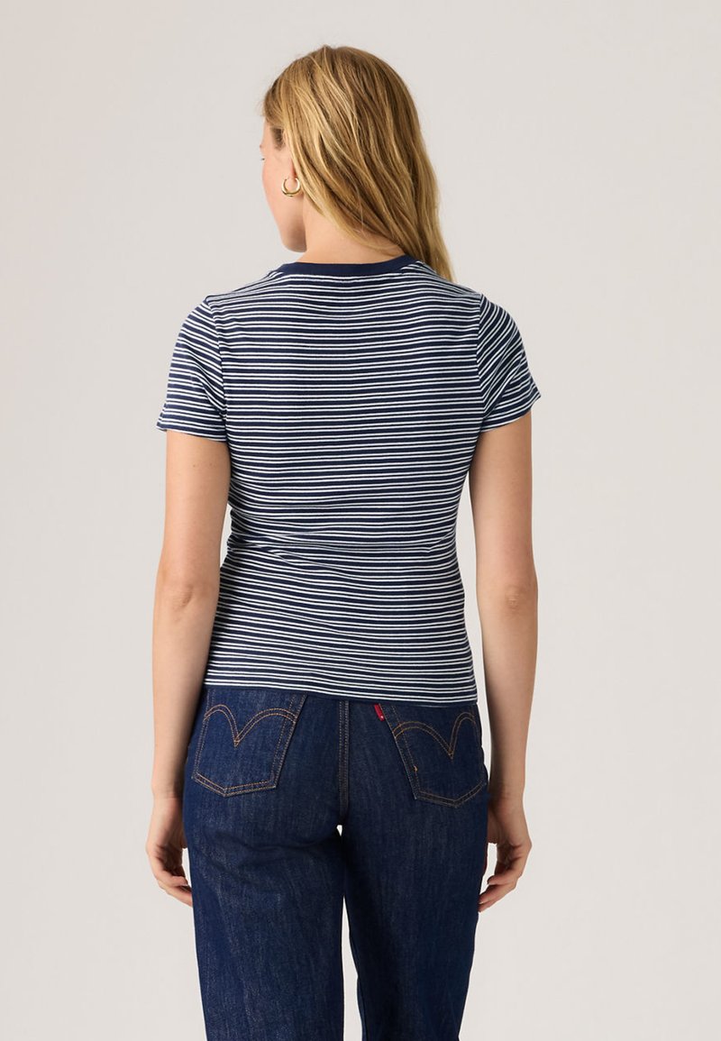 Maglietta a righe navy e bianche con maniche corte, vestibilità slim, scollo rotondo, tessuto morbido, mostrata di schiena, abbinata a jeans in denim scuro.