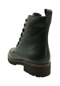 Bota de tobillo de cuero negro con cordones en la parte delantera, suela gruesa negra, detalle de costura marrón y lengüeta trasera para tirar.