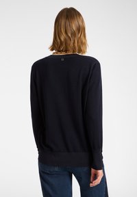 Marineblauer Strickpullover mit rundem Ausschnitt, langen Ärmeln und geradem Saum. Mit einem kleinen Logo-Akzent auf dem oberen Rücken.