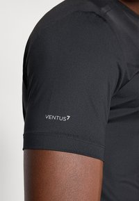 Melns īsu piedurkņu sporta krekls ar teksturētu audumu. Ir redzams "VENTUS7" logo uz kreisās piedurknes, bezšuvju šuvēji.