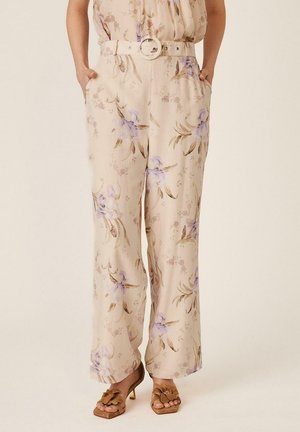 Pantalones beige de pierna ancha con estampado floral morado, cintura alta, cinturón a juego con hebilla redonda, usados con sandalias marrones de tacón.