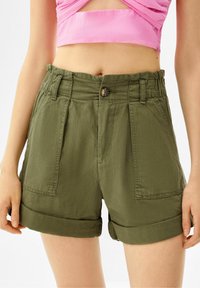 Olivgröna shorts med avslappnad passform, med knappstängning, uppvikta fållar och framfickor. Tillverkade av lättviktigt tyg.