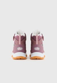 Des chaussures avec un design montante, en matériau synthétique violet, avec des accents texturés et une doublure en molleton blanc, le tout reposant sur des semelles en caoutchouc orange.