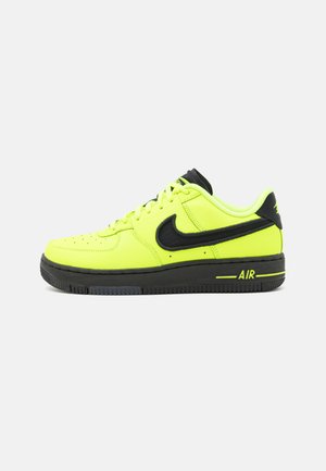Baskets Nike Air avec une tige en cuir jaune vif, des accents noirs et une semelle en caoutchouc texturé affichant le mot "AIR". Design bas.