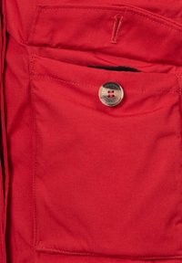 Rødt stof med en glat tekstur har en stor forlomme, en sølvfarvet knappelukning og kontrasterende syningsdetaljer.