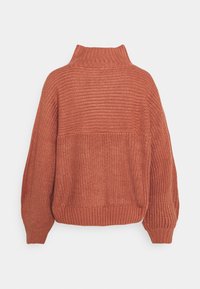 Pull en maille épaisse couleur rouille avec col roulé côtelé haut, manches longues bouffantes, poignets et ourlet côtelés.